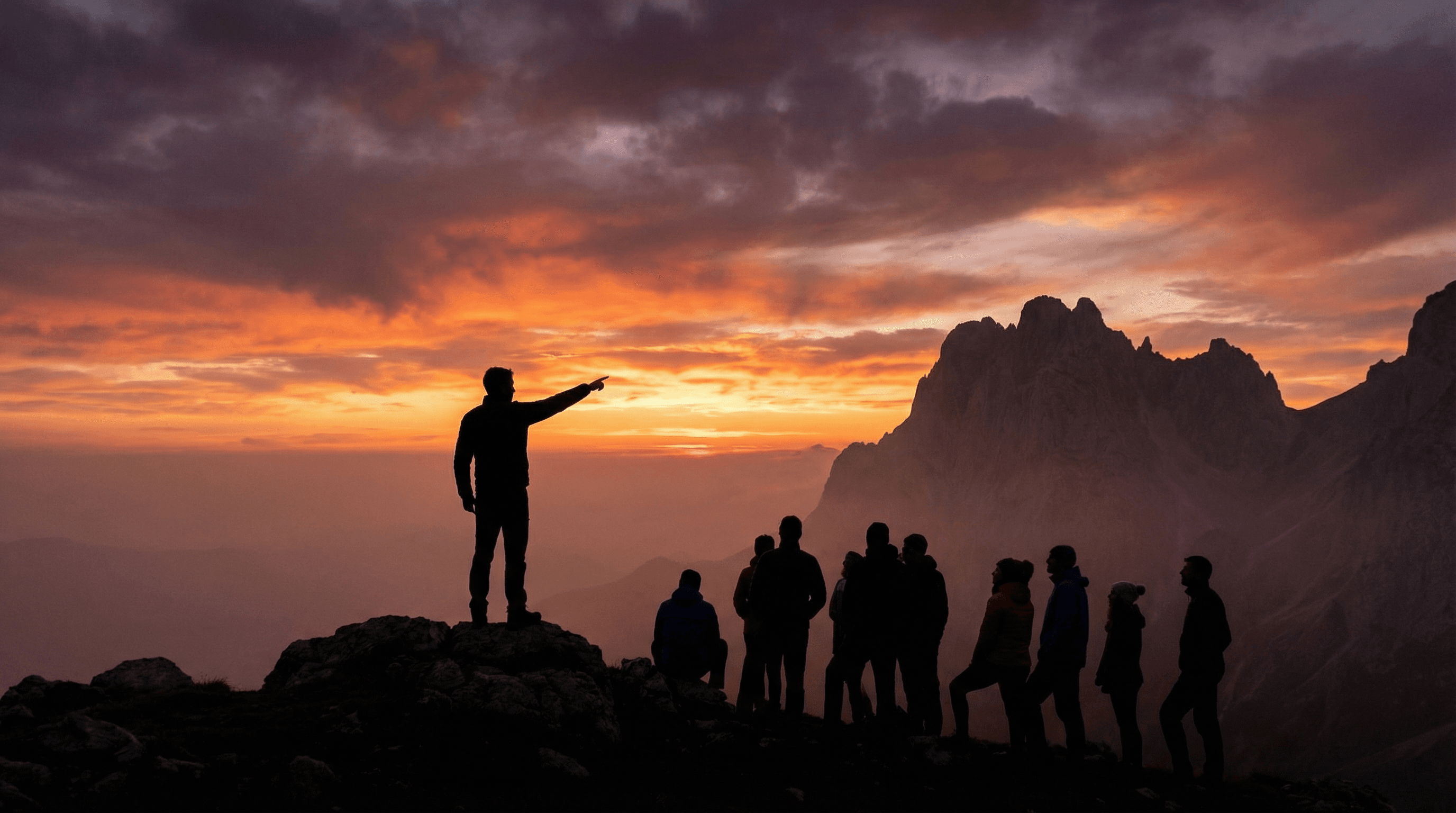 遠くの山を指差すリーダーと、その言葉に耳を傾ける仲間たちのシルエットイラスト